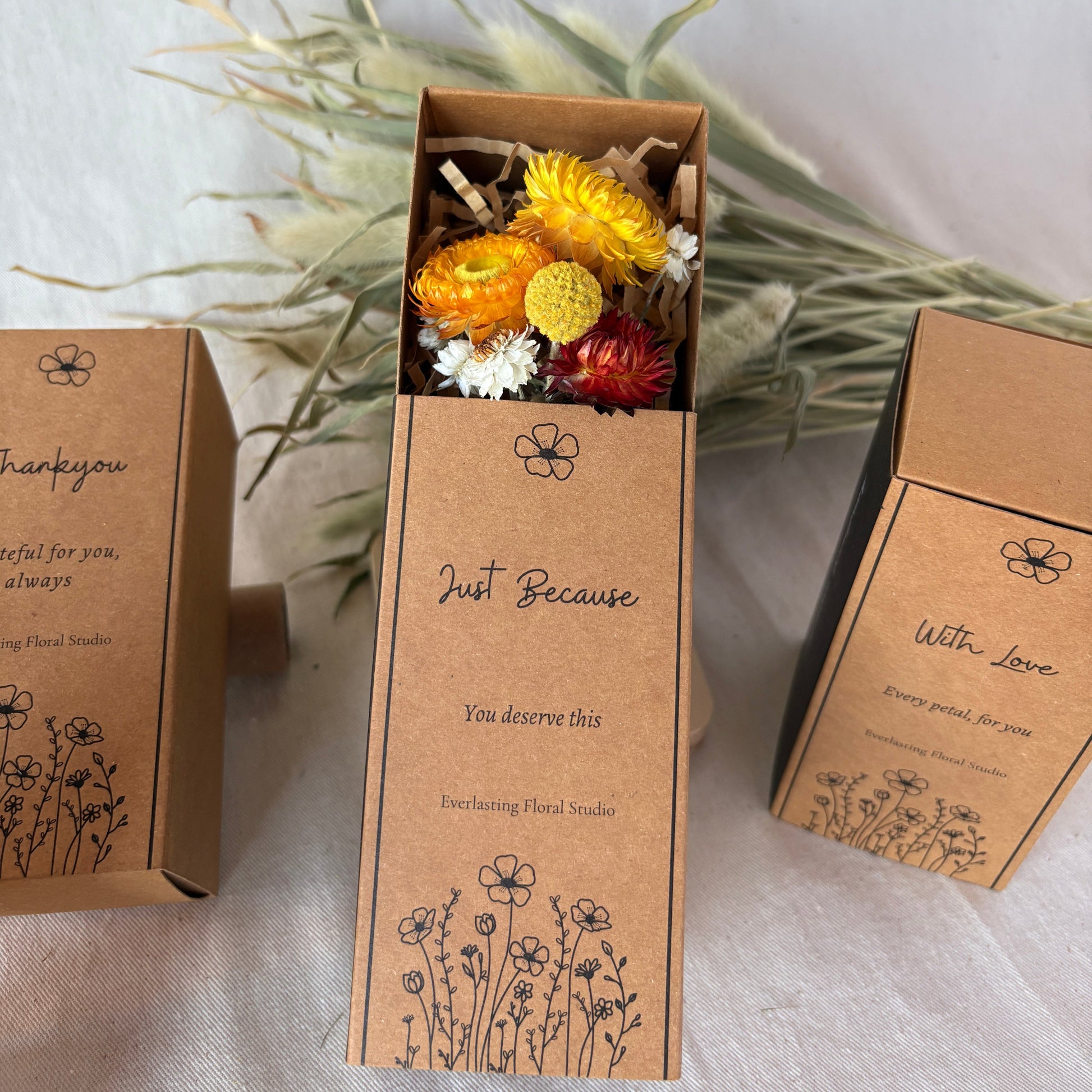 Brown cardboard box with dried flowers on a white fabric background