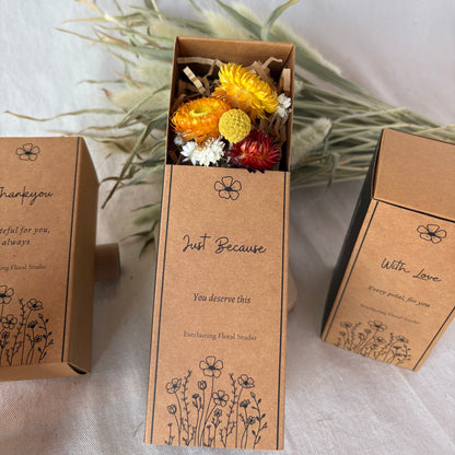 Brown cardboard box with dried flowers on a white fabric background