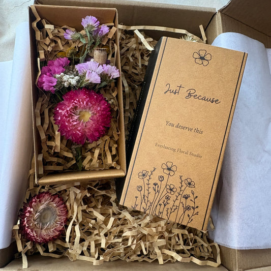 Box with dried flowers and a card labeled 'Just Because' on a white background
