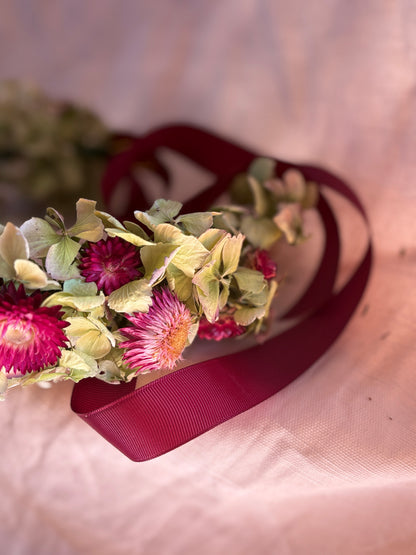 Floral flower crown with pink flowers and green leaves on a soft pink background