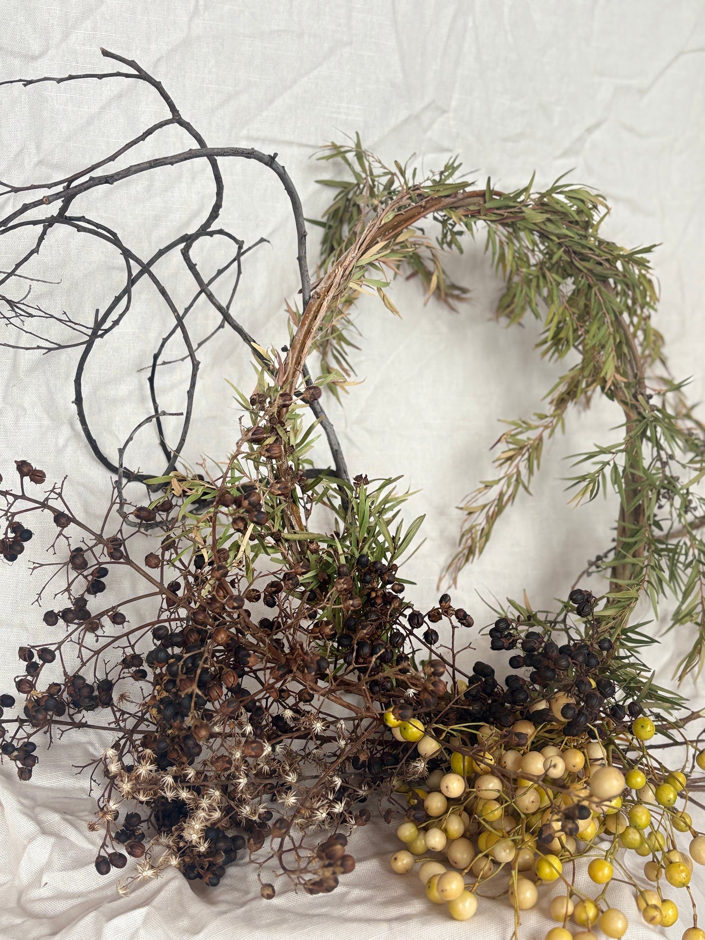 Decorative wreath with greenery and berries on a textured white background