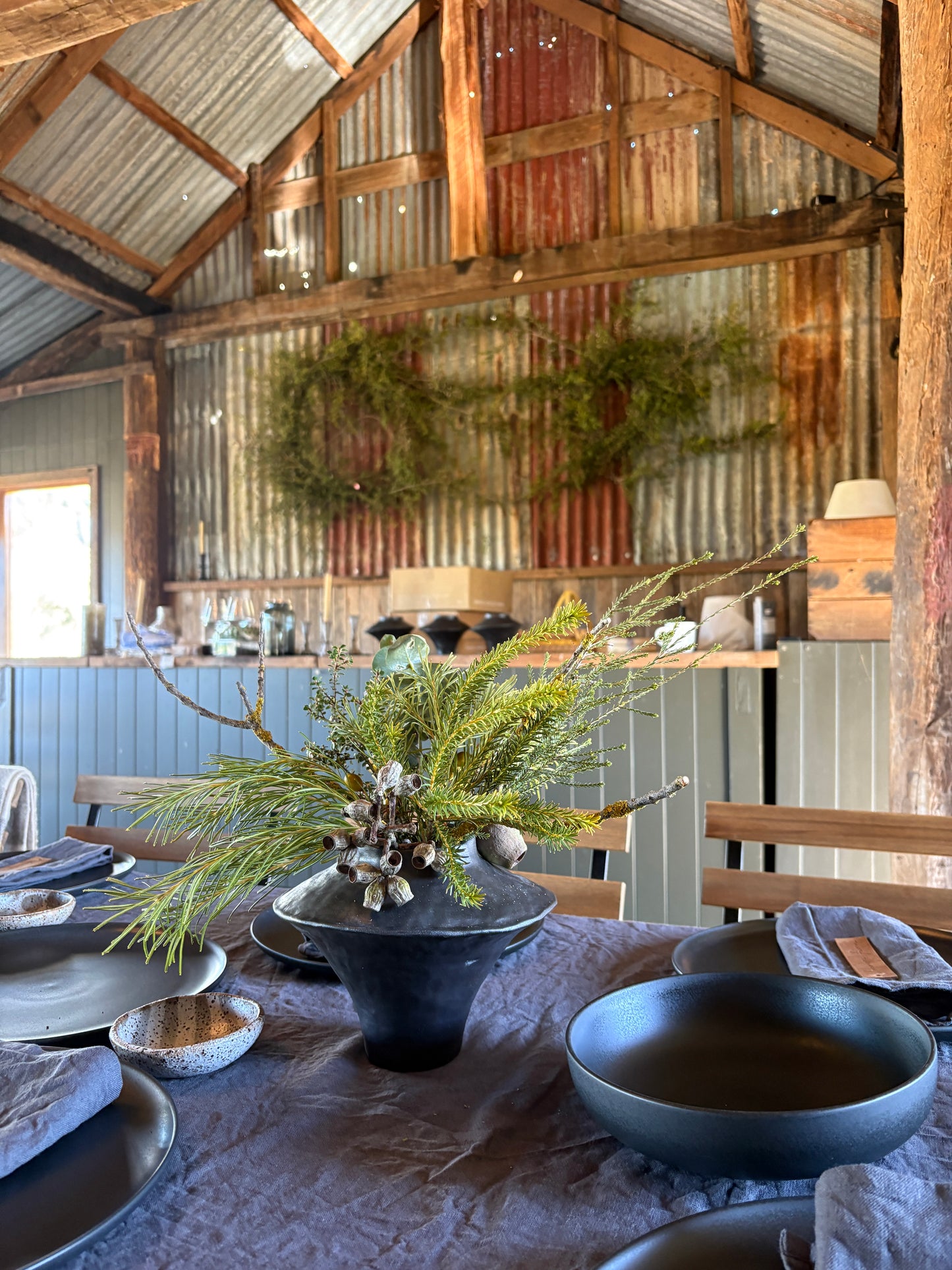 Dining area with rustic wooden walls, a table set with blue bowls and a decorative plant.
