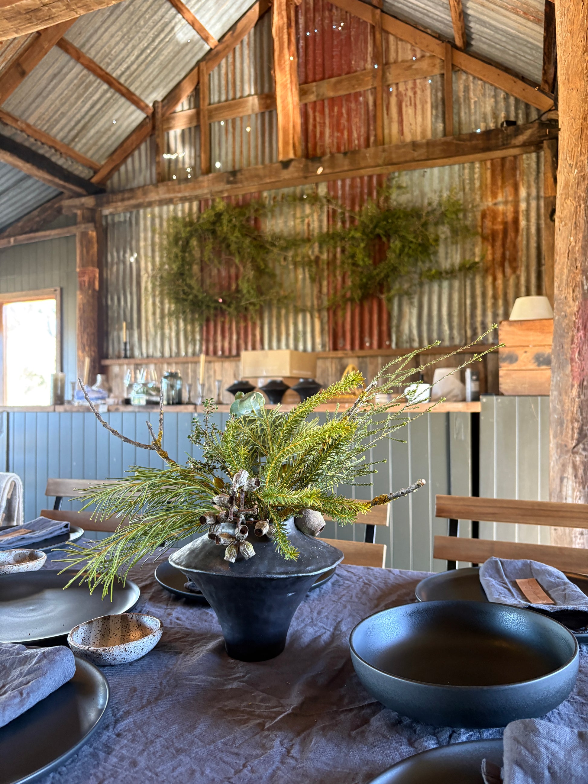 Dining area with rustic wooden walls, a table set with blue bowls and a decorative plant.