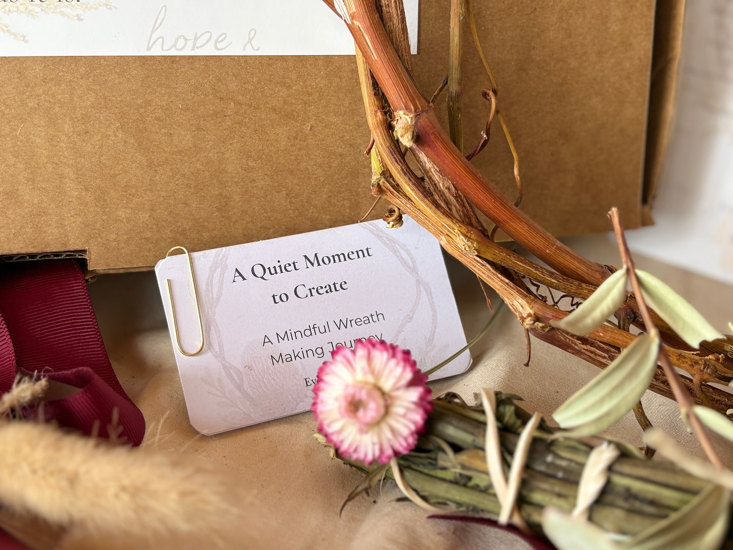 Wreath-making kit with materials and a card on a cardboard surface