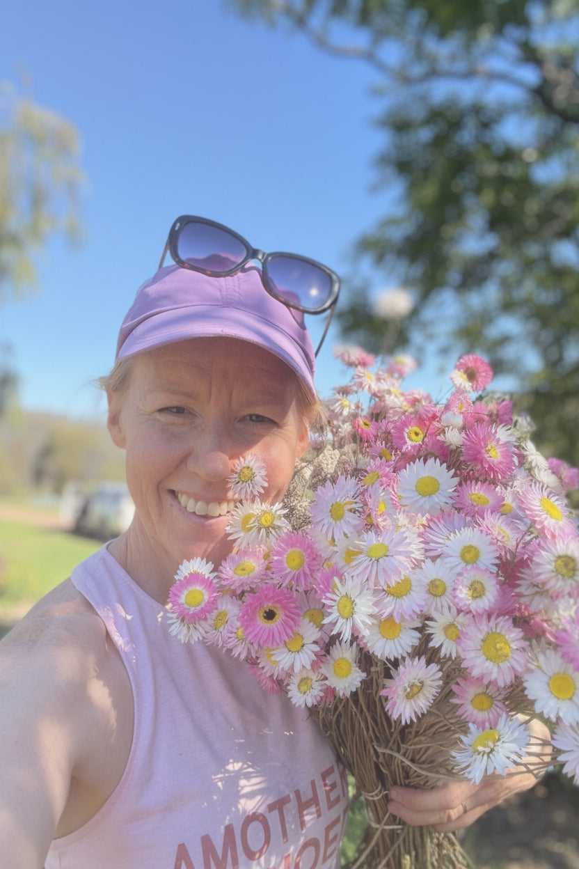 Person holding a bouquet of flowers outdoors on a sunny day