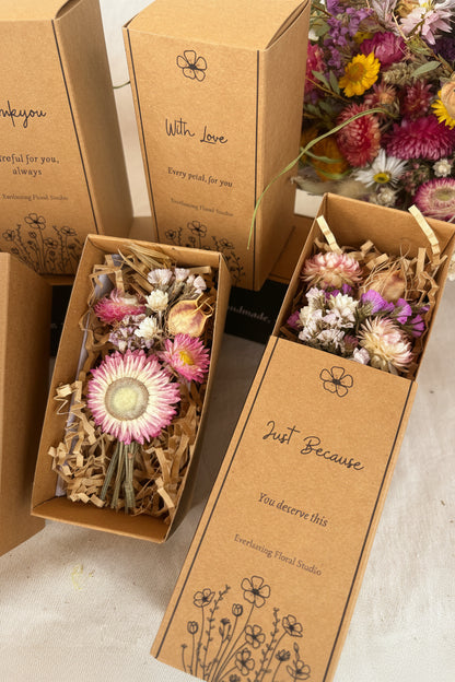 Brown gift boxes with dried flowers and decorative text on a light background